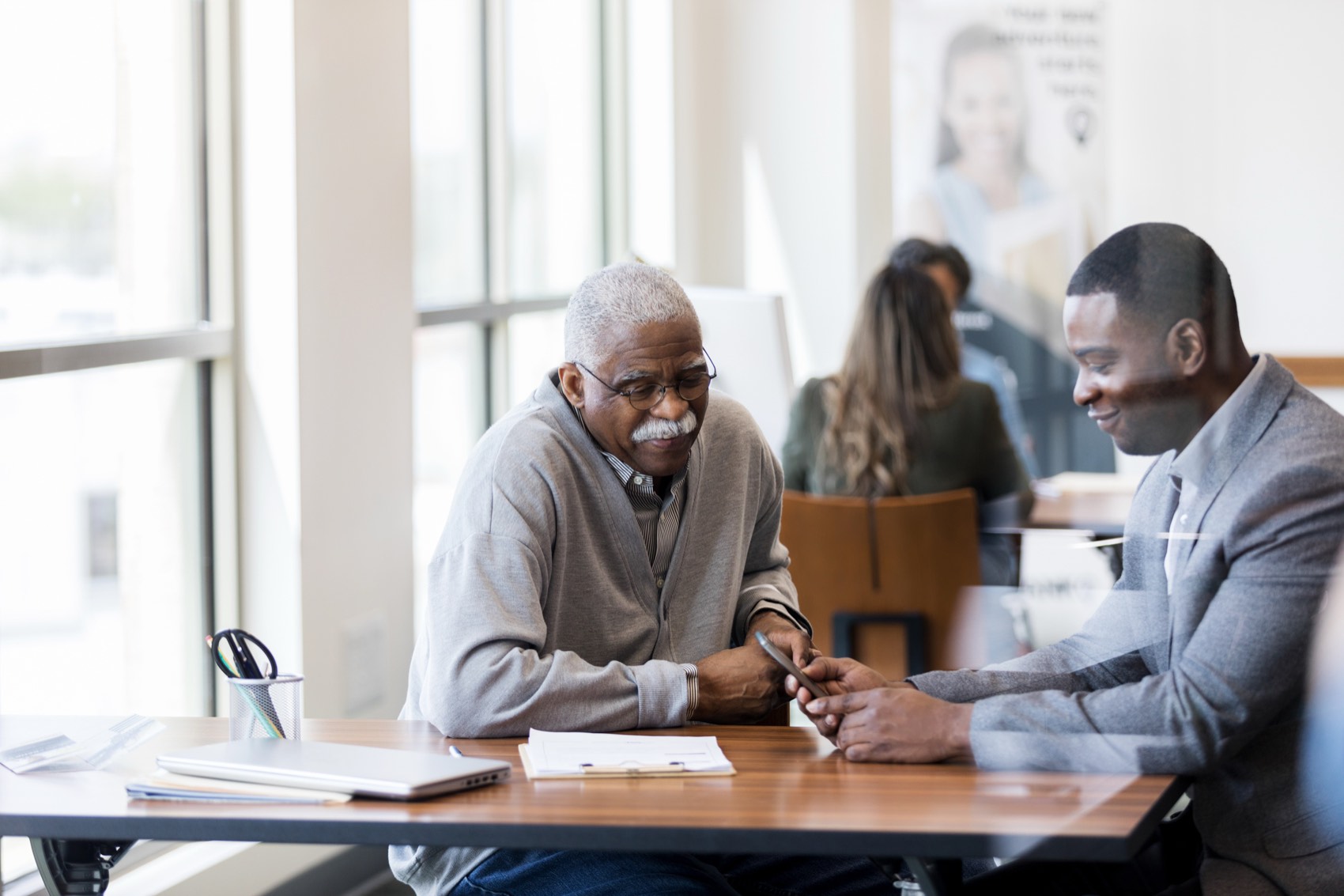 Two men reviewing financial documents together at a table.