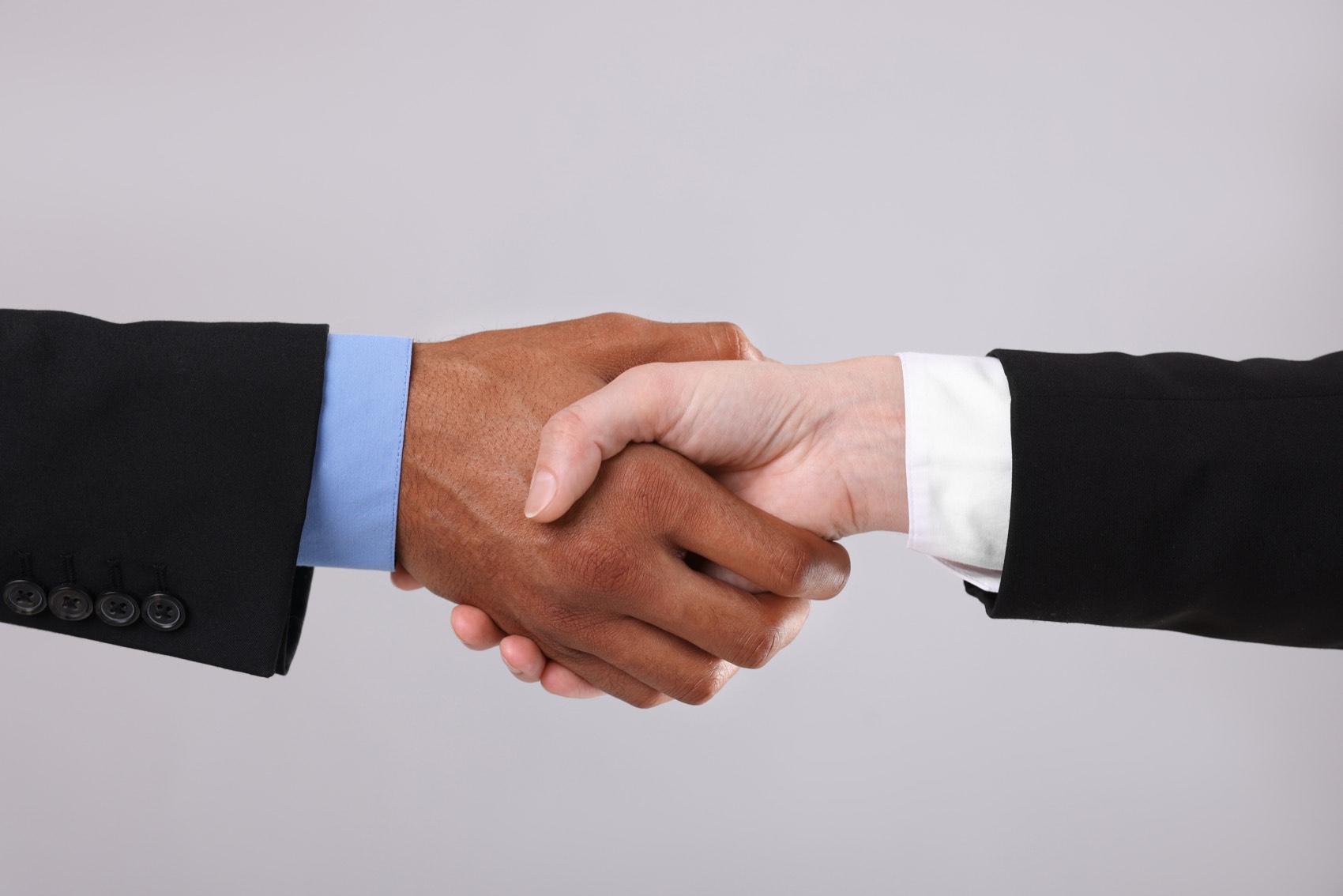 Two people shaking hands to close a partnership agreement.