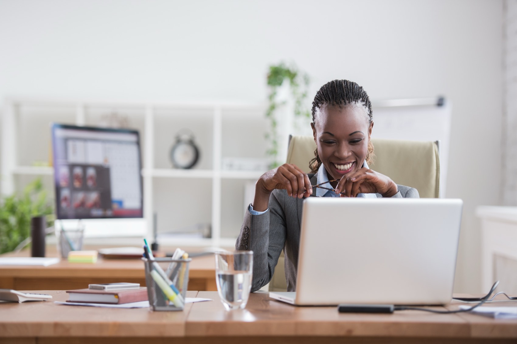 A business professional smiling while reviewing data on a laptop.